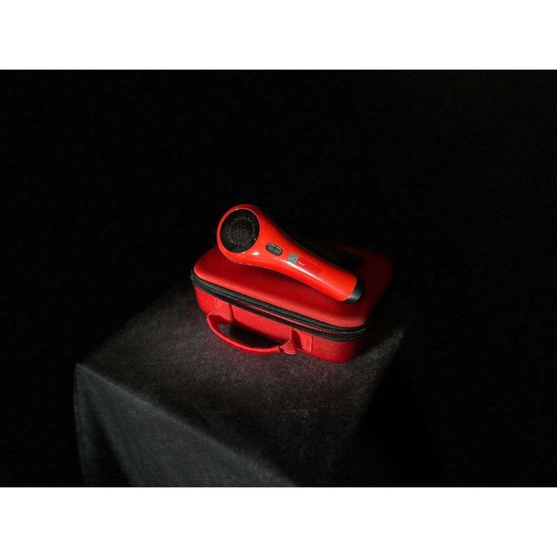 Red handheld 3b cold laser with a black cover on a dark surface