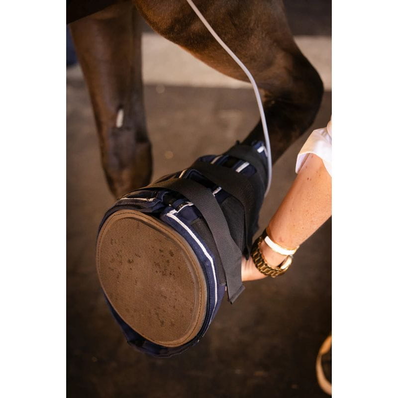 Horse leg with a protective boot being adjusted by a person.