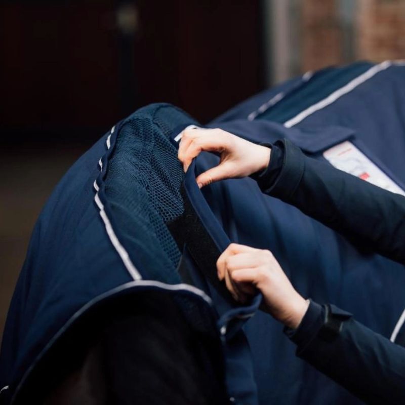 Person adjusting a dark blue jacket with white accents