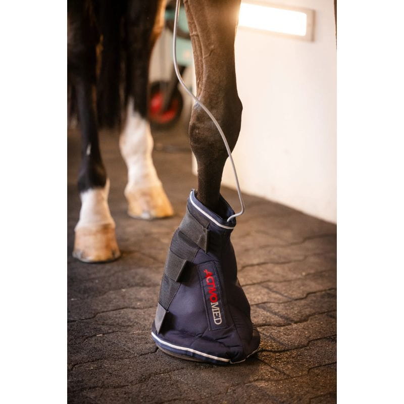 Horse leg with protective boot on a stable floor