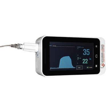 A handheld pulse oximeter with a white casing and a black screen displaying oxygen saturation and pulse waveforms. A clear cable is plugged into the side of the device.