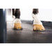 Close-up of a horse's hooves with yellow protective boots on treadmill floor.