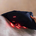 Black massage pillow with red lights on a person's back against a beige wall.